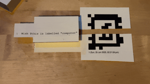 gif showing a finger touching pieces of paper, that when pressed mimic pressing a button on a computer (and trigger a digital response)
