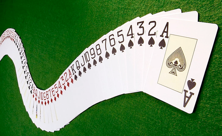 A deck of playing cards fanned out on a green surface