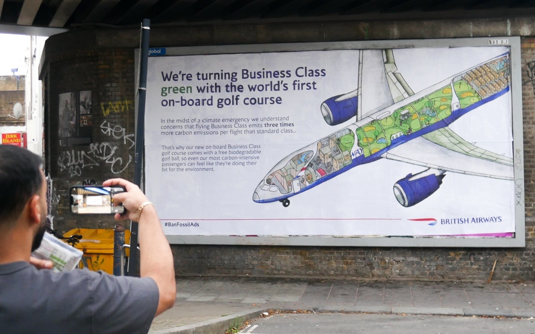 Billboard with a cross-section illustration of a plane, depicting a golf-course onboard. Accompanying text description reads as follows: We're turning Business Class green with the world's first on-board golf course. In the midst of a climate emergency we understand concerns that flying Business Class emits three times more carbon emissions per flight than standard class... That's why our new on-board Business Class golf course comes with a free biodegradable golf ball, so even our most carbon-intensive passengers can feel like they're doing their bit for the environment.