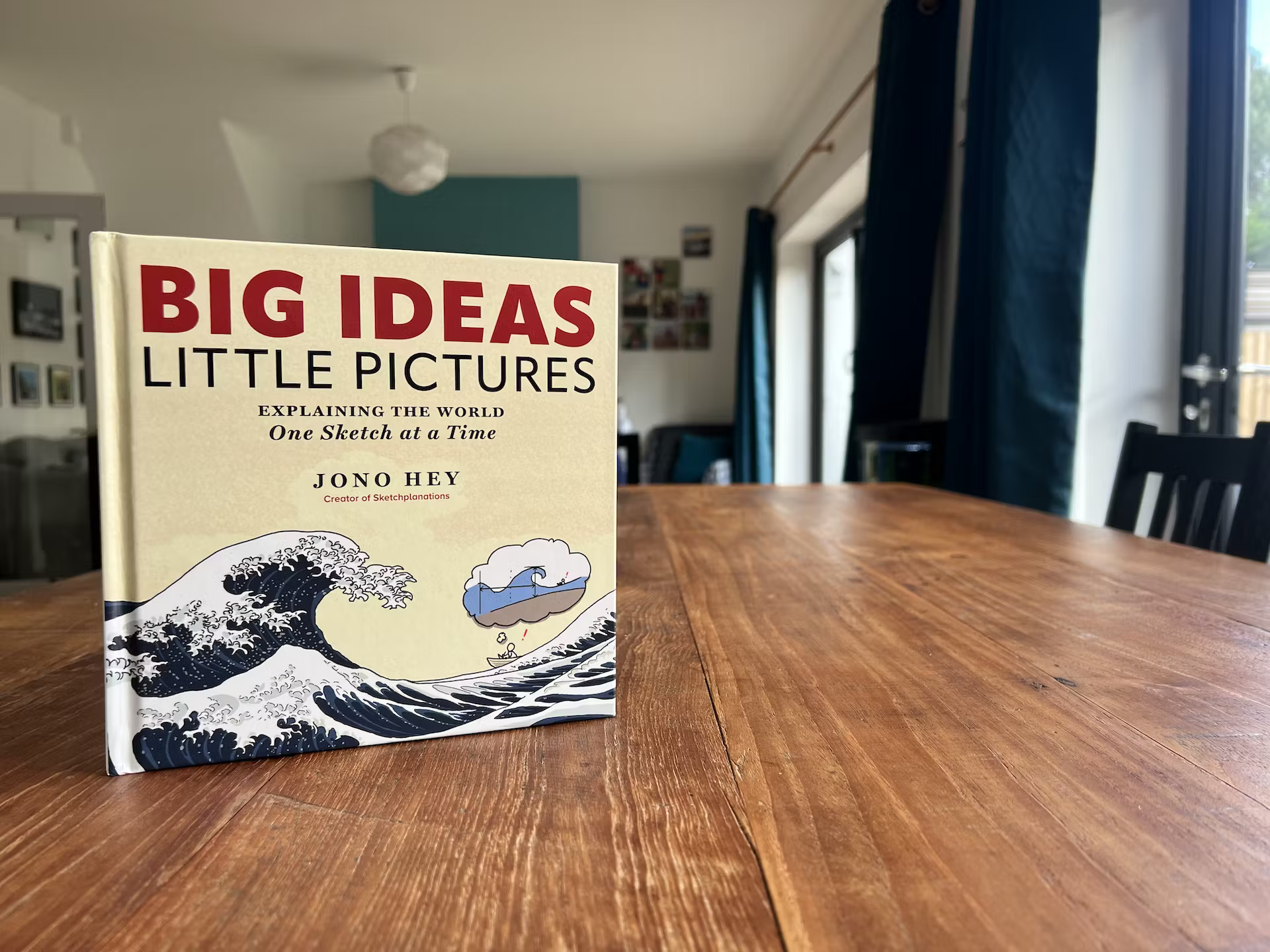 Photo of the book Big Ideas Little Pictures standing on a wooden table.
