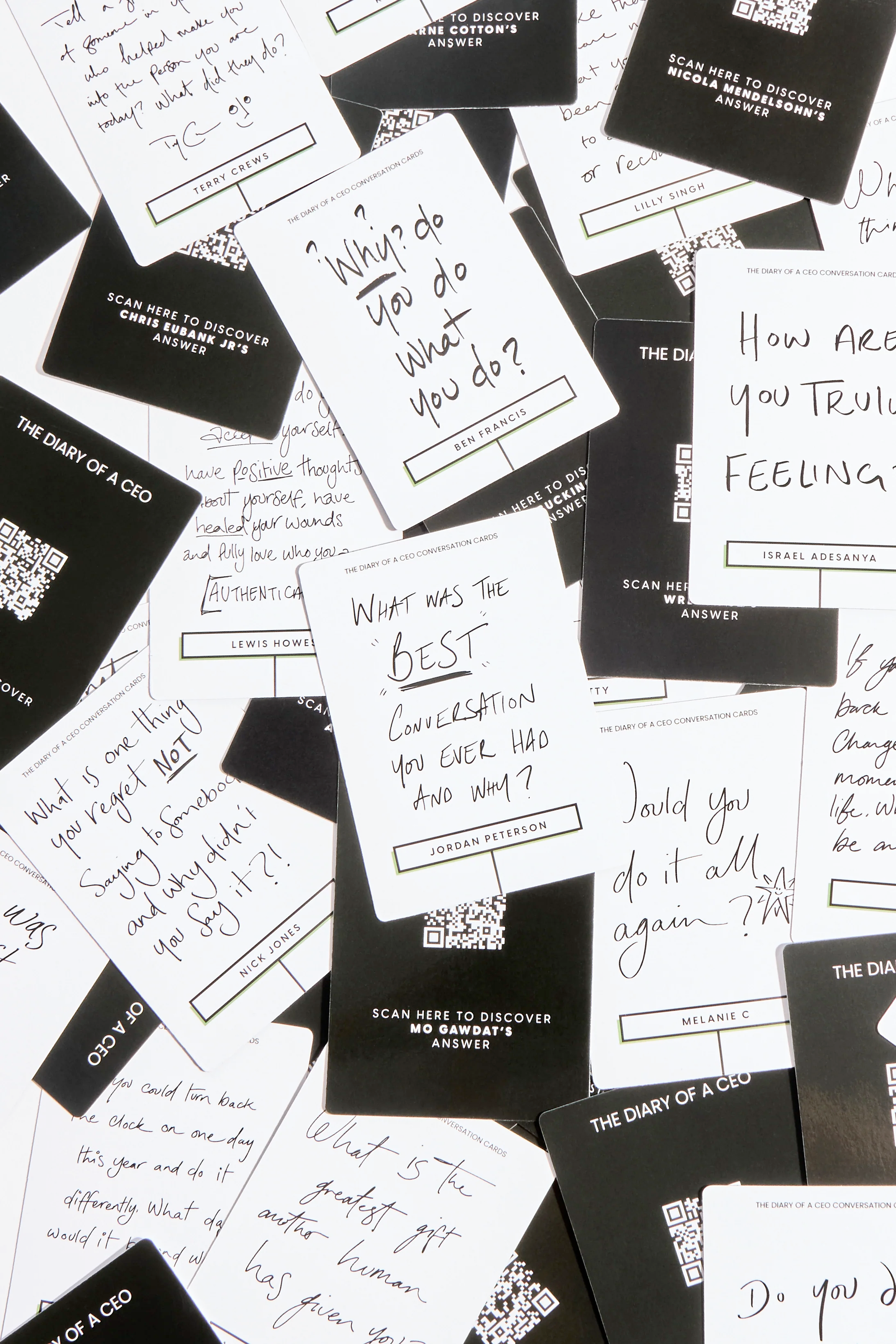 A bunch of the Diary of a CEO Card Deck cards scattered on a table. You can see how each card question is written in someone’s unique handwriting.