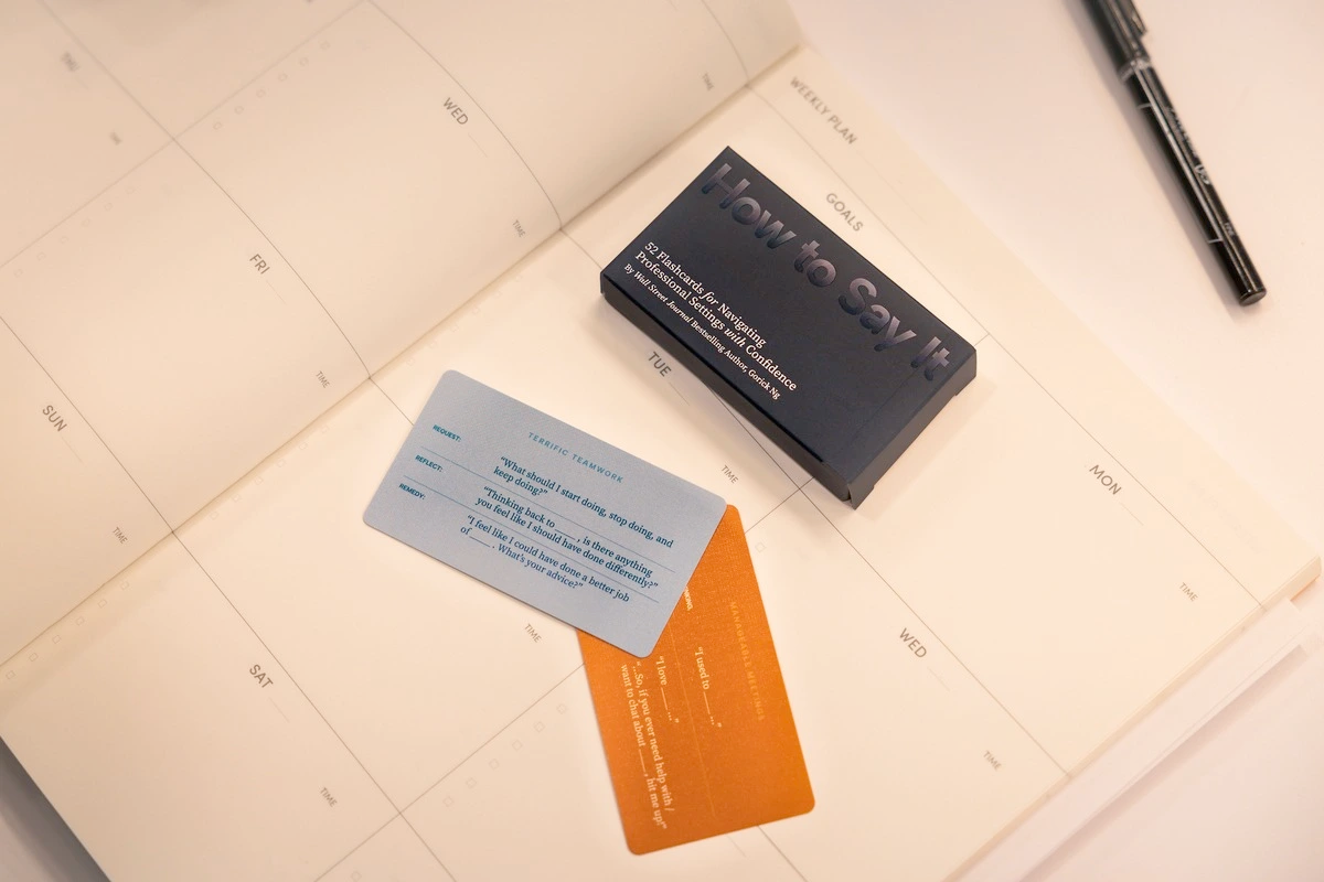 Picture of a "How to Say It" box, with two cards pulled from this and casually arranged on top of a desk calendar.