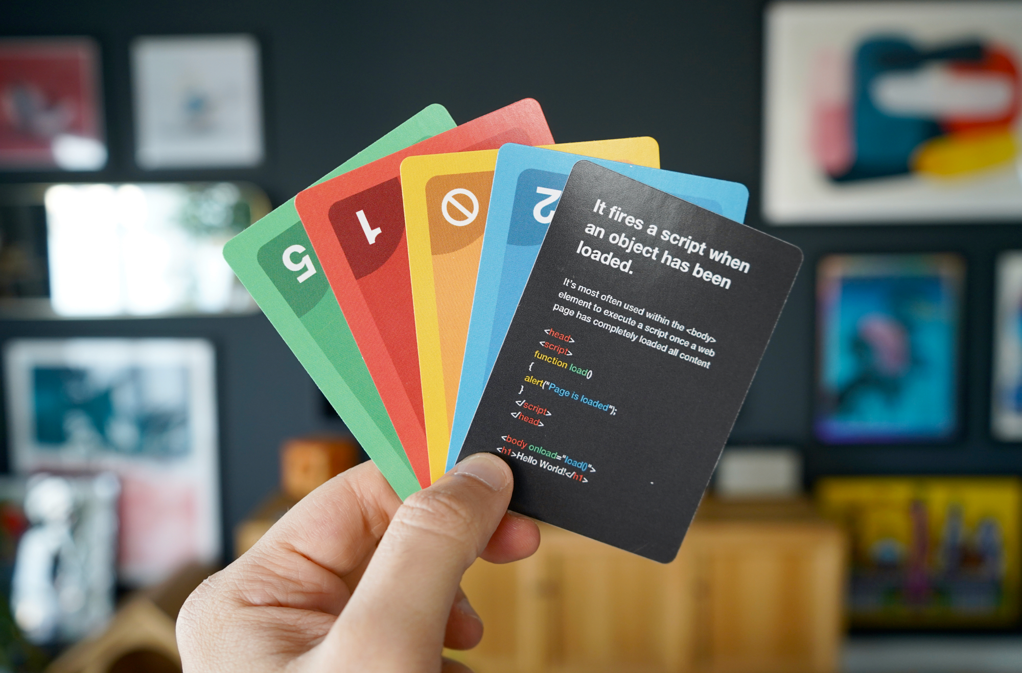 Photo of a hand holding several brightly colored cards; the front card describes a coding question. 