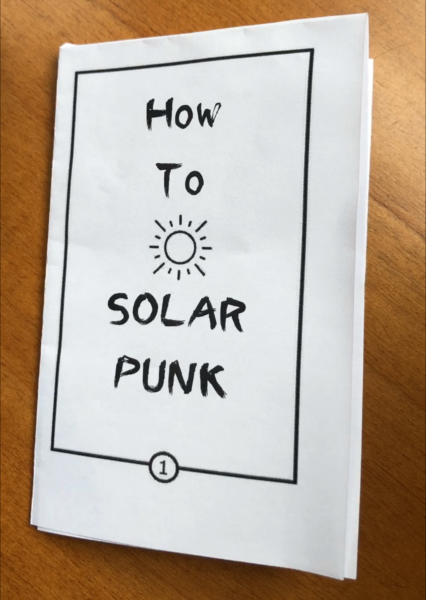 Photo of the How to Solarpunk zine, cut out, folded, and resting on a table.