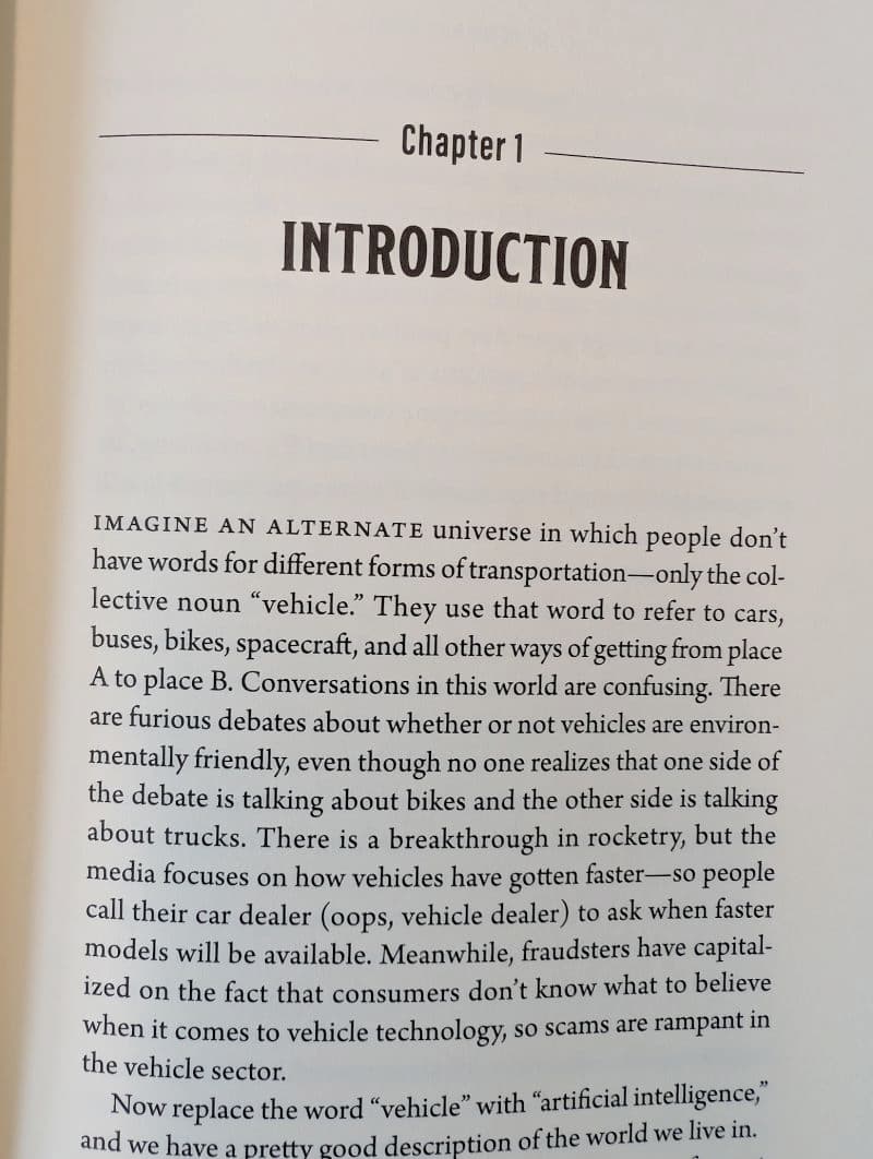 Photo of the first page of a book. Text reads: "IMAGINE AN ALTERNATE universe in which people don't have words for different forms of transportation —only the collective noun "vehicle." They use that word to refer to cars, buses, bikes, spacecraft, and all other ways of getting from place A to place B. Conversations in this world are confusing. There are furious debates about whether or not vehicles are environmentally friendly, even though no one realizes that one side of the debate is talking about bikes and the other side is talking about trucks. There is a breakthrough in rocketry, but the media focuses on how vehicles have gotten faster-so people call their car dealer (oops, vehicle dealer) to ask when faster models will be available. Meanwhile, fraudsters have capitalized on the fact that consumers don't know what to believe when it comes to vehicle technology, so scams are rampant in the vehicle sector. Now replace the word "vehicle" with "artificial intelligence," and we have a pretty rood description of the world we live in.Now replace the word "vehicle" with "artificial intelligence," and we have a pretty rood description of the world we live in."